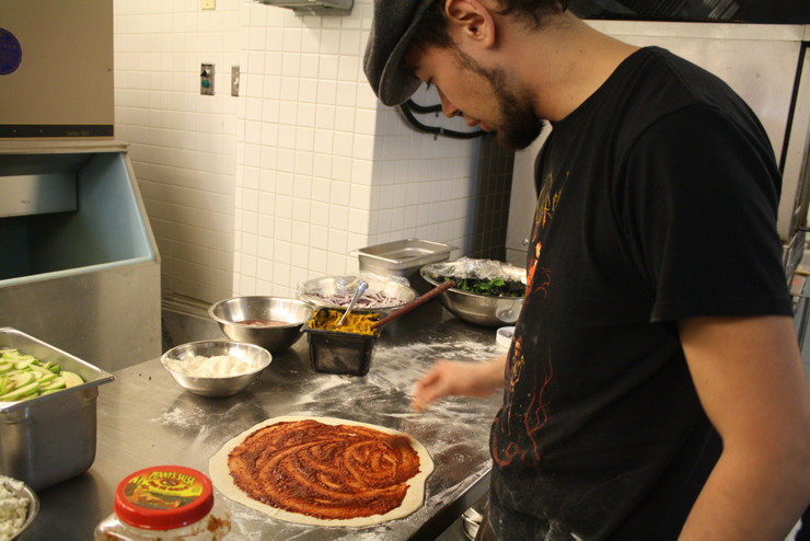 Resident Member Riley Iwamoto makes pizza in the Green College kitchen